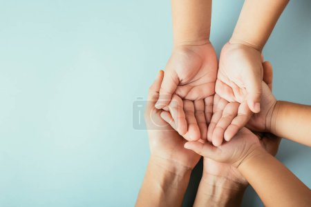 Top view parents and little kid holding empty hands together studio shot isolated on blue background, family home, hands children on adult mother hand, help support, parents family day concept