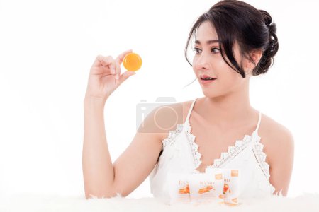Téléchargez les photos : Asiatique jeune belle femme souriant shes tenant orange artisanale savon bio soin de la peau près du visage pour le présent produit isolé sur fond blanc, Beauté zéro déchet concept - en image libre de droit
