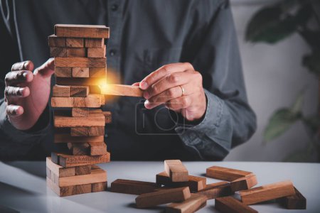 Photo for Alternative risk plan. Business hand playing tower wooden blocks game, man pull one wood block from tower he clenched his fist, show great joy in accomplishing it, Business gambling growth concept - Royalty Free Image