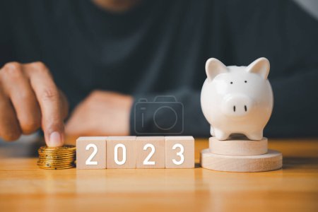 Photo for Happy New Year 2023. Businessman with wood cubes block number years 2023 and piggy bank to setting target plan business goal, Start finance success business, save money - Royalty Free Image