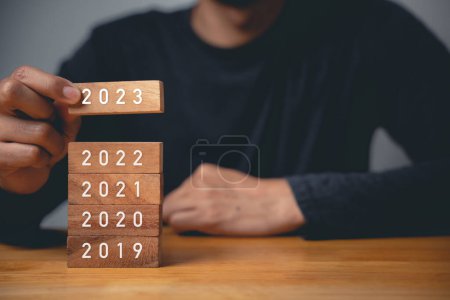 Photo for Happy New Year 2023. Businessman hand holding years 2023 number wooden block to put it above the previous year, Business risk management, solution, Resolution, strategy, goal - Royalty Free Image