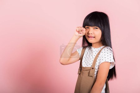 Téléchargez les photos : Unhappy children. Asian little kid 10 years old bad mood her cry wipe tears with fingers at studio shot isolated on pink background, child girl stress feeling sad unhappy crying - en image libre de droit