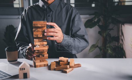 Photo for Alternative risk plan. Business hand playing tower wooden blocks game, man pull one wood block from tower he clenched his fist, show great joy in accomplishing it, Business gambling growth concept - Royalty Free Image