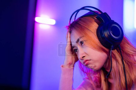 Photo for Game Over. Asian gamer playing online video game she losing and sad on computer PC colorful neon LED lights, young woman in gaming headphones feeling disappointed about lost game, E-Sport concept - Royalty Free Image