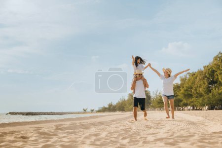 Foto de Día de la familia. La gente feliz de la familia que se divierte en vacaciones de verano corre en la playa, hija cabalgando en la espalda del padre y madre corriendo en la playa de arena, viaje familiar jugando juntos al aire libre, viajando en vacaciones - Imagen libre de derechos
