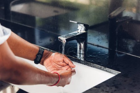 Téléchargez les photos : Gros plan lavage des mains de l'homme noir frottement avec du savon et de l'eau dans les éviers pour prévenir l'épidémie coronavirus hygiène pour arrêter la propagation du virus, hygiène pour le nettoyage en quarantaine concept COVID-19 - en image libre de droit