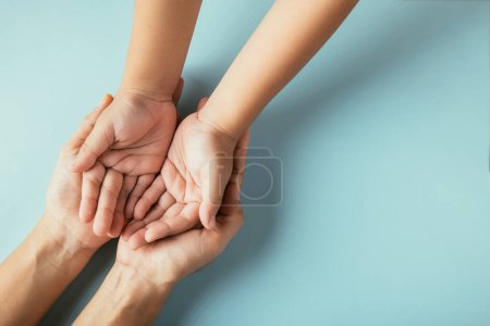 Closeup top view family hands stack palms studio shot isolated on blue background, parents and kid holding empty free space on hand together, Gesture sign of support and love, Family and parents day