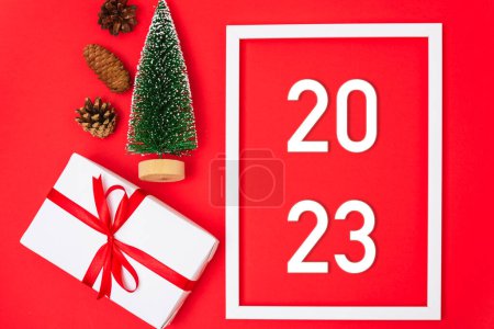 Téléchargez les photos : Bonne année 2023 fond. Bannière Cadeaux et décorations de Noël avec 2023 ans nombre sur fond rouge, Plat, vue de dessus, espace de copie - en image libre de droit