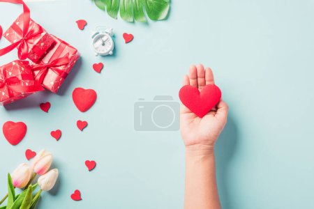 Photo for Valentines day and birthday. Woman hands holding red heart and have gift or present box decorated surprise on blue background, Females hand hold heart have gift box package in craft paper - Royalty Free Image