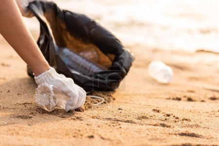 Téléchargez les photos : Femme bénévole cueillette bouteille en plastique dans une poubelle sac en plastique noir pour le nettoyage de la plage, femme nettoyer les ordures, concept écologique et Journée mondiale de l'environnement, Save earth concept - en image libre de droit