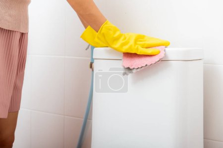 Photo for Hands of Asian woman cleaning toilet seat by pink cloth wipe restroom at house, female wearing yellow rubber gloves she sitting and cleanup or washing bathroom, Housekeeper healthcare concept - Royalty Free Image