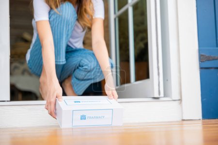 Photo for Close up hands of sick Asian woman sitting at door to receive medication first aid pharmacy box from hospital delivery service at floor home, female patient buy drugstore online business, healthcare - Royalty Free Image