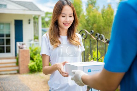 Photo for Delivery man give medicine drug to patient female at home, Sick Asian young woman receive medication first aid pharmacy box from hospital delivery service, healthcare medicine online concept - Royalty Free Image
