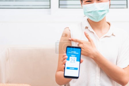 Photo for Asian young woman pointing to adhesive plaster on arm her vaccinated and showing app smartphone mobile digital screen vaccinated coronavirus COVID-19 certificate after getting vaccine to prevent - Royalty Free Image