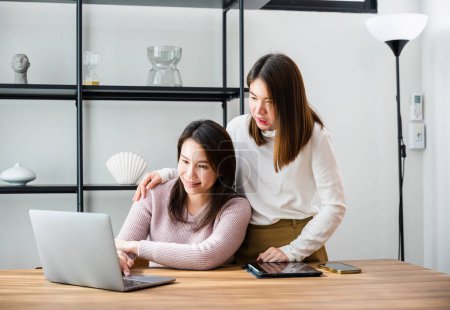 Téléchargez les photos : Asiatique femme d'âge moyen et l'adolescence ils magasinent en ligne sur ordinateur, mère et adolescente fille regardant ordinateur portable au bureau à la maison, heureux travail de famille ensemble - en image libre de droit