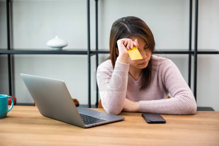 Foto de Mujer asiática preocupada que tiene problemas con la tarjeta de crédito bloqueada rechazó el pago en línea en el ordenador portátil, Mujer estresada calcular los ingresos mensuales de los gastos del hogar no es suficiente - Imagen libre de derechos
