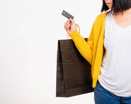 Photo for Happy woman hand she wears yellow shirt holding black shopping bags and credit card, young female hold black packets within arms isolated on white background, Black Friday sale concept - Royalty Free Image