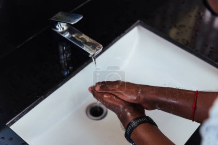 Foto de Primer plano lavándose las manos de hombre negro frotándose con jabón y agua en los lavabos para evitar brotes coronavirus higiene para dejar de propagar virus, higiene para la limpieza de cuarentena concepto COVID-19 - Imagen libre de derechos
