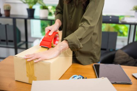 Photo for Close up hands young woman sealing with tape big cardboard box, female hand packing box delivery products shipment to customers, small business startup - Royalty Free Image
