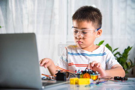 Téléchargez les photos : Asiatique enfant garçon assemblage roue dans Arduino robot voiture devoirs, Petit enfant essayer d'assembler construire roue à jouet de voiture, la création électronique IA technologie atelier leçon d'école en ligne - en image libre de droit