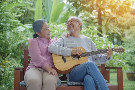 Glückliches asiatisches Seniorenpaar älterer Mann, der Gitarre spielt, während seine Frau zu Hause im Freien zusammen singt, Aktivität Familiengesundheit, Lebensstil im Ruhestand genießen und Spaß an Senioren haben