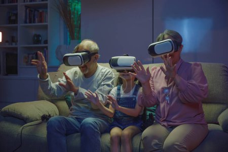 Téléchargez les photos : Asiatique petite-fille et grands-parents jouer ensemble passionnant intéressant jeux vidéo en utilisant la réalité virtuelle casque salon à la maison, les personnes âgées avec enfant jouer jeu vidéo VR, divertissement familial - en image libre de droit