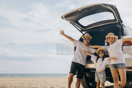 Téléchargez les photos : Parents et enfants voyageant en vacances à la plage de la mer, famille s'amuser en vacances d'été sur la plage ciel bleu, Les gens qui apprécient le voyage sur la route se tiennent sur le dos leur voiture lever les bras et la main, Bonne journée de la famille - en image libre de droit