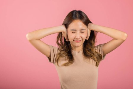 Photo for Asian portrait beautiful young woman have close ears with hand palms and close eyes, studio shot isolated on pink background, Thai female covering ears for loud noise with copy space, bad pressure - Royalty Free Image