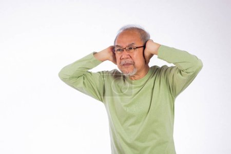 Foto de Deaf. Portrait senior old man with glasses sad covering ears with fingers hands studio shot isolated on yellow background, Asian unhappy elder man Suffering from a loud sound ignoring someone - Imagen libre de derechos