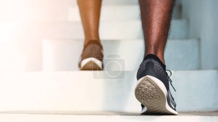 Foto de Cerca de los zapatos de atleta de las piernas joven corredor del deporte hombre negro paso corriendo hasta subir escaleras haciendo entrenamiento ejercicio de cardio deporte en la calle al aire libre, ejercicio saludable antes del concepto de entrenamiento - Imagen libre de derechos