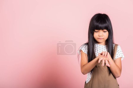 Téléchargez les photos : Asian little kid 10 years old scratching itch back hand from mosquito bite at studio shot isolated on pink background, Child girl dermatitis and scabies, Allergy symptoms, healthcare and medicine - en image libre de droit