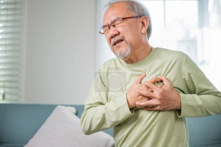 Téléchargez les photos : Asiatique homme âgé ont une maladie congénitale souffrant de chagrin d'amour seul à la maison, homme âgé mauvaise douleur main toucher la poitrine ayant une crise cardiaque, vieillesse problèmes de santé de retraite malsain malade - en image libre de droit