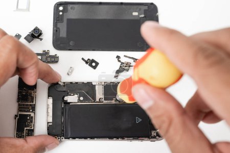 Téléchargez les photos : Technician repairing inside the smartphone motherboard with tools for recovery, The man repair by tightening nut from mobile phone with a screwdriver to fix problem - en image libre de droit