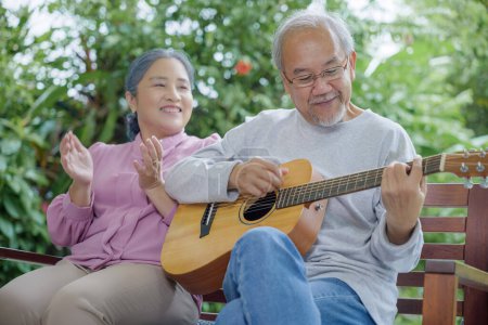 Photo for Happy two Asian senior couple elderly man playing the guitar while his wife is singing together at home outdoors, Enjoying lifestyle during retirement life having fun, Activity family health care - Royalty Free Image