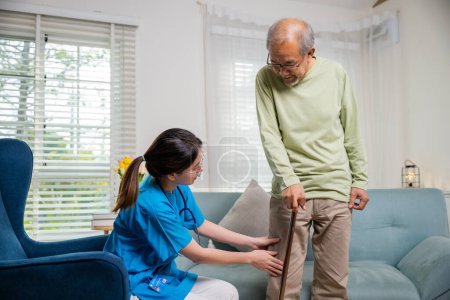 Foto de Asiática joven enfermera comprobar la rodilla y la pierna después de la cirugía de anciano anciano paciente que sufre de dolor en la rodilla, médico preguntando anciano hombre acerca de síntoma de dolor con bastón - Imagen libre de derechos