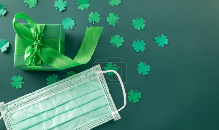 Photo for Top View flat lay of paper cut clover leaves festive decor and Medical face mask, shamrocks leaf holiday symbol on colour background, New normal for coronavirus quarantine, Happy St Patricks Day - Royalty Free Image