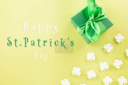 Foto de Happy St Patricks Day decoration background concept. Top view gift box green clover leaves, shamrocks leaves holiday symbol with copy space on pastel yellow background - Imagen libre de derechos