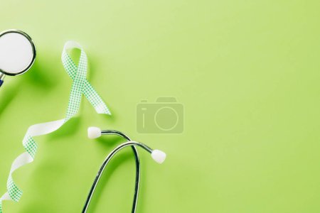 Téléchargez les photos : Green awareness ribbon and doctor stethoscope symbol of Gallbladder and Bile Duct Cancer month on green background with copy space, concept of medical and health care support, World bipolar day - en image libre de droit