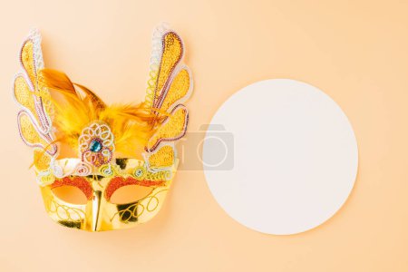 Téléchargez les photos : Happy Purim carnival decoration. Golden venetian ball mask isolated on pastel background, Jewish Purim, Mardi Gras in Hebrew, holiday background banner design with circle white space, Masquerade party - en image libre de droit