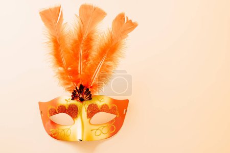 Téléchargez les photos : Joyeux carnaval Pourim décoration. Masque de boule vénitienne avec plume rouge sur fond pastel avec espace de copie, fête masquée, Pourim juif en hébreu, conception de bannière de fond de vacances - en image libre de droit