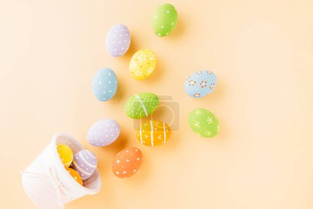 Foto de Top view easter eggs in basket filled fall down spread isolated on pastel background, Happy Easter Day, Creative composition banner web design holiday background, flat lay top view - Imagen libre de derechos