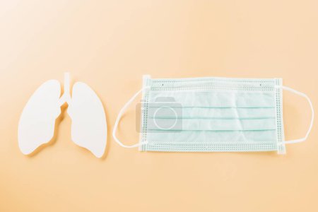 Photo for World TB Day. Overhead lungs paper symbol and facial medical face mask on pastel background, lung cancer awareness, copy space concept of world tuberculosis day, banner background - Royalty Free Image