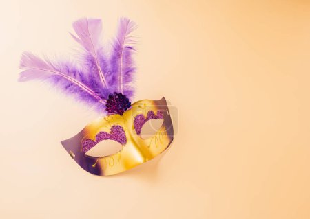 Téléchargez les photos : Happy Purim carnival decoration. Jewish Purim and Mardi Gras in Hebrew, Top view venetian ball mask with purple feather on pastel background, holiday background banner design, Masquerade party - en image libre de droit