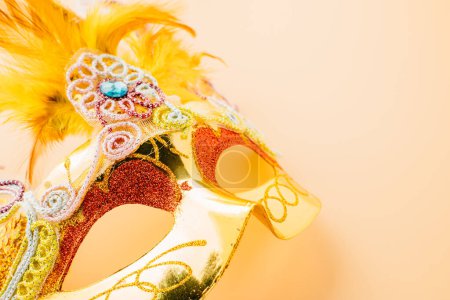 Happy Purim carnival decoration. Close up golden venetian ball mask isolated on pastel background, Jewish Purim or Mardi Gras in Hebrew, holiday background banner design, Masquerade party