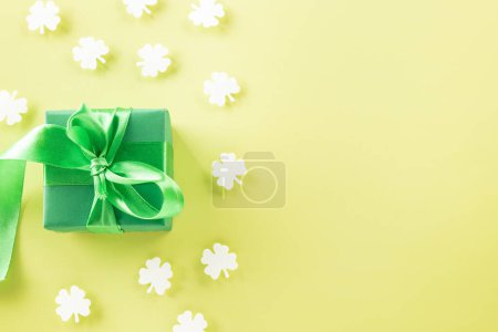 Photo for Happy St Patricks Day decoration background concept. Top view gift box green clover leaves, shamrocks leaves holiday symbol with copy space on pastel yellow background - Royalty Free Image