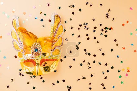 Foto de Happy Purim carnival decoration. Jewish Purim and Mardi Gras in Hebrew, celebration holiday background banner design, Golden venetian ball mask, carnival mask isolated on pastel background - Imagen libre de derechos
