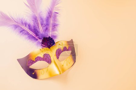 Foto de Happy Purim carnival decoration. Top view venetian ball mask with purple feather on pastel background, Jewish Purim and Mardi Gras in Hebrew, holiday background banner design, Masquerade party - Imagen libre de derechos