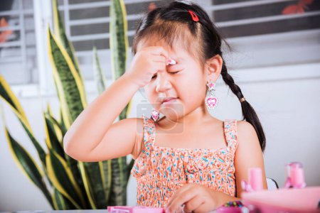 Photo for Happy kid is beautiful make up with cosmetics toy, Asian adorable funny little girl making makeup her face she applying carborundum eyeliner to eyelid, Learning activity to be woman at house - Royalty Free Image