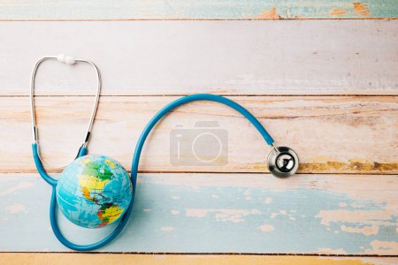Téléchargez les photos : Journée mondiale de la santé. Stéthoscope médecin bleu et globe du monde isolé sur fond bois avec espace de copie, Save world day, Green Earth, Santé et concept médical - en image libre de droit