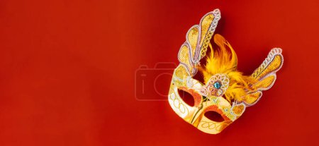 Foto de Happy Purim carnival. Carnival mask for Mardi Gras celebration isolated on red background banner design with copy space, jewish holiday, Purim in Hebrew holiday carnival ball, Venetian mask - Imagen libre de derechos